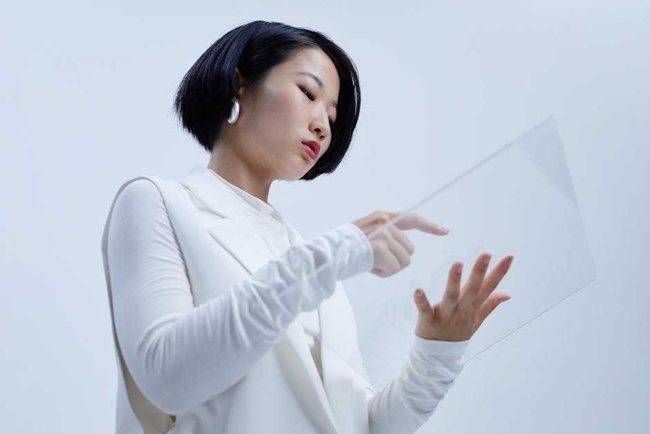 An Asian woman interacting with a transparent device in a modern setting, wearing stylish white attire.